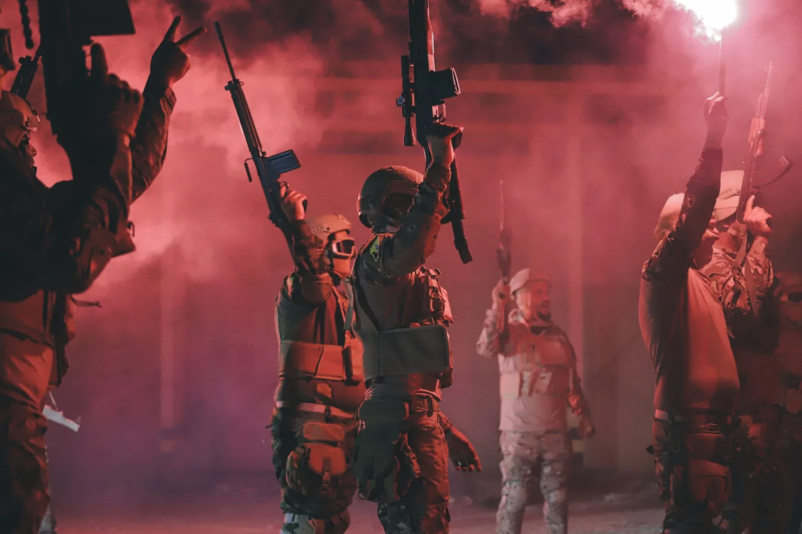 Soldados libios sosteniendo rifles y bengalas rojas en una escena militar dinámica.