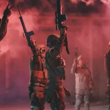 Soldados libios sosteniendo rifles y bengalas rojas en una escena militar dinámica.