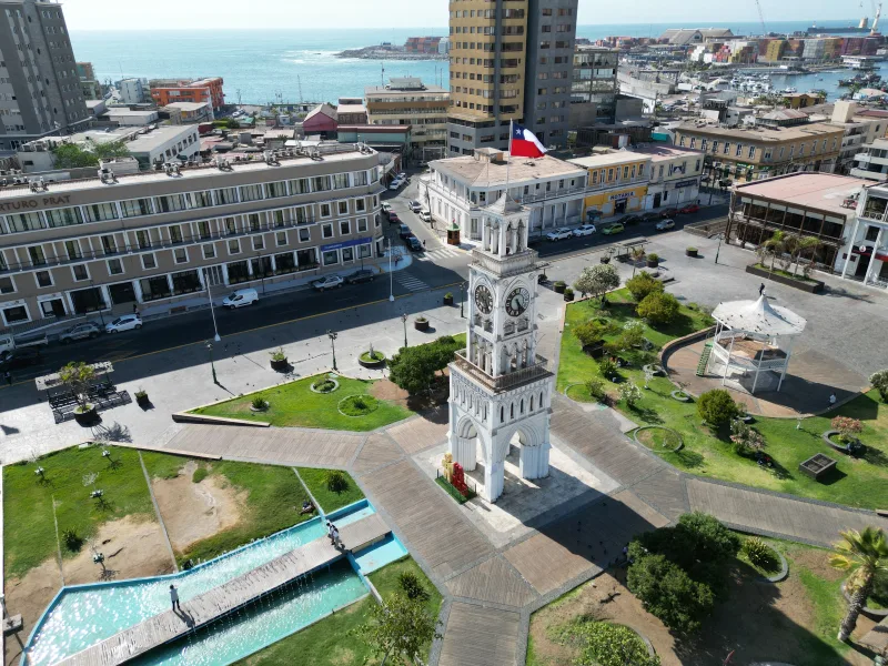 A stunning aerial view of the Clock Tower in Plaza Prat, Iquique, Chile, showcasing urban architecture and coastal beauty.