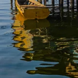 A rustic boat floats beside a wooden pier at sunset in Maracaibo, Venezuela, creating serene reflections.