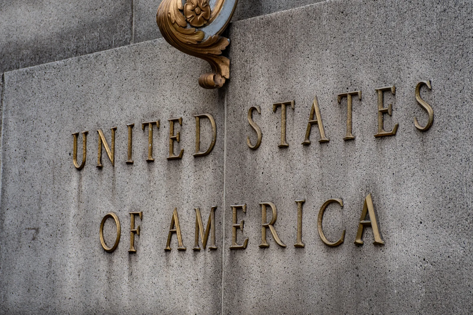 Primer plano del texto «Estados Unidos de América» en un muro de piedra de estilo vintage.