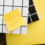 Motivational quote 'Aspire to inspire' on a sticky note placed on books. Minimal and inspirational visual.