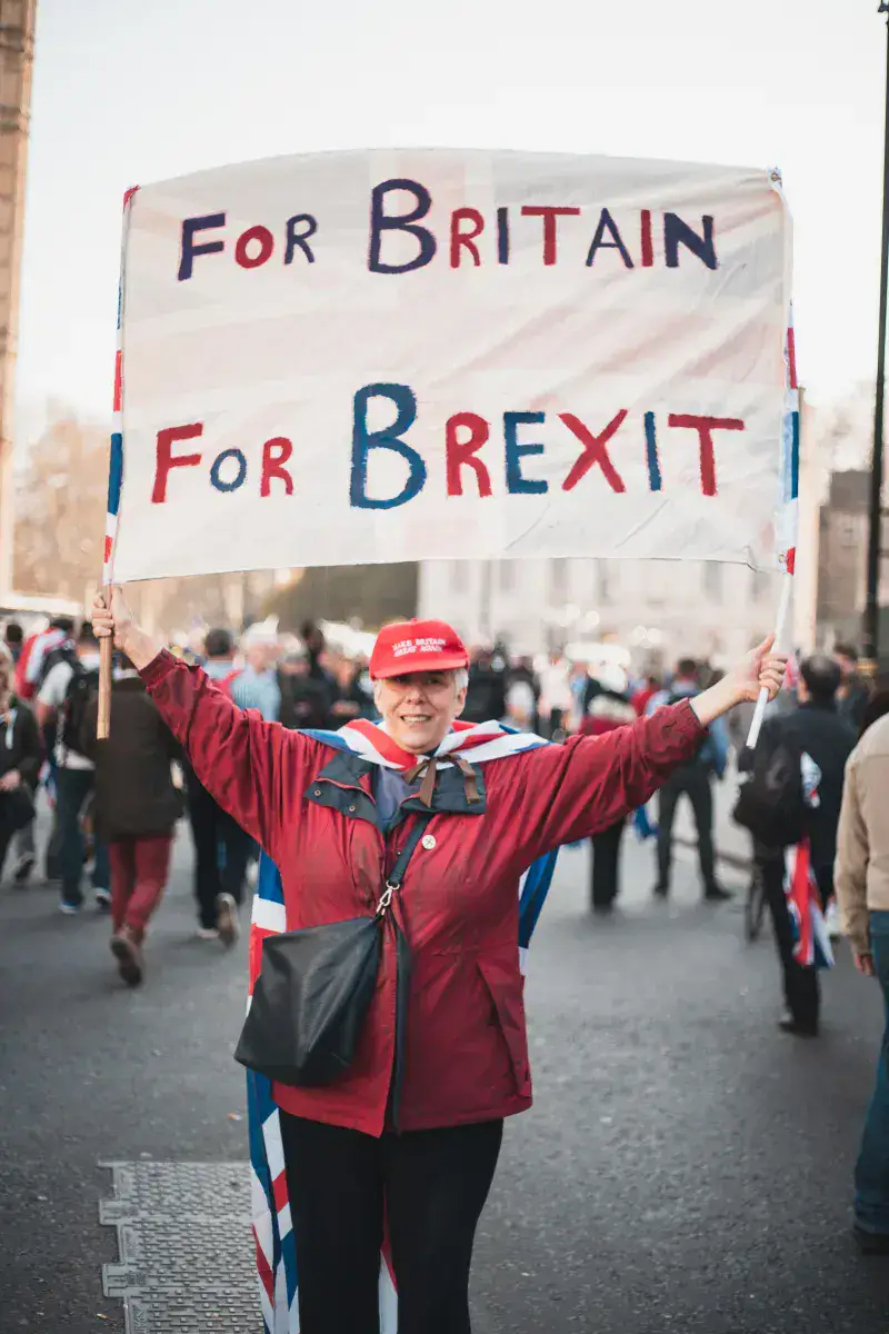 Woman in red jacket holding a 'For Britain For Brexit' sign during a protest in London.