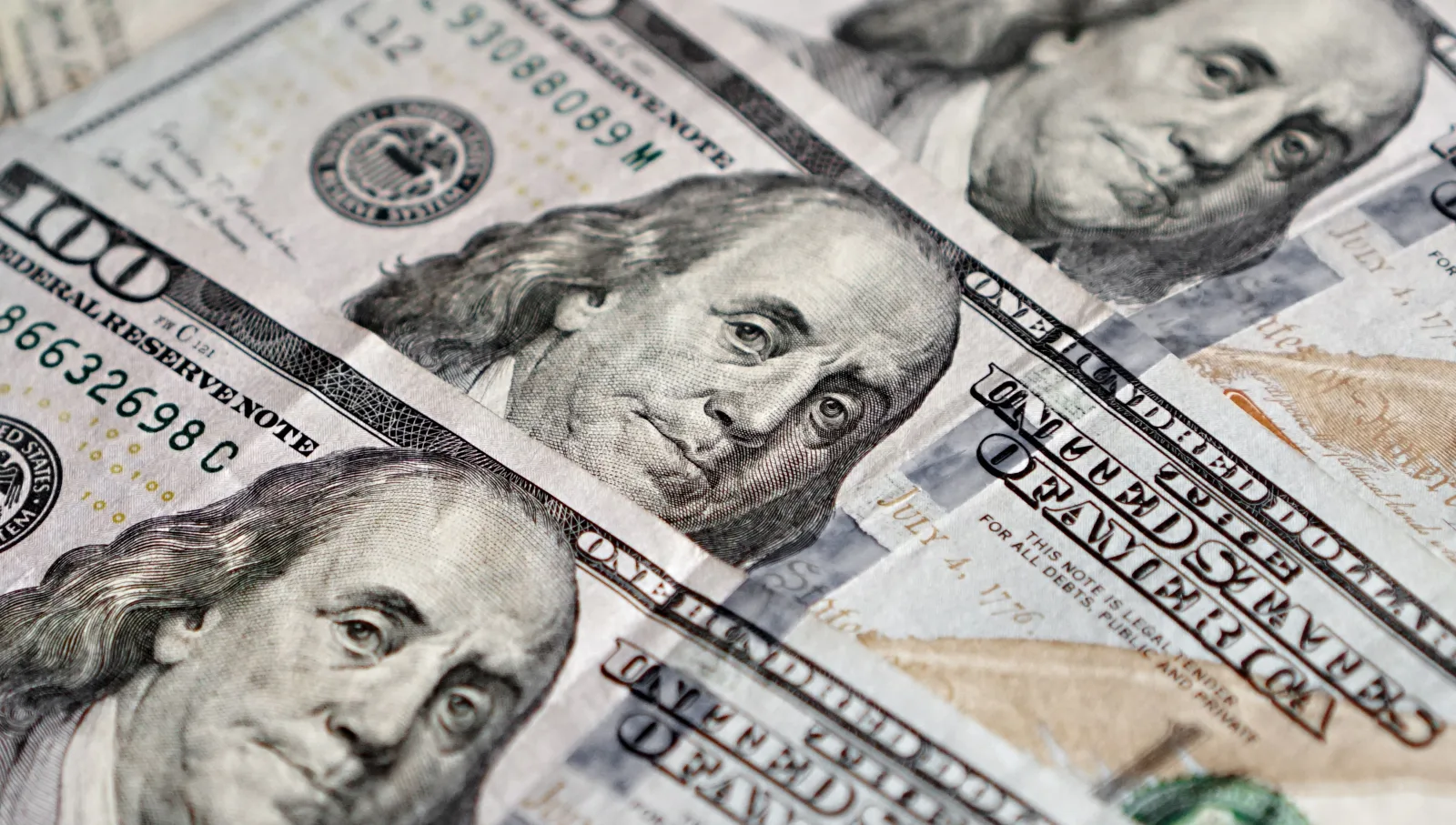 Vista detallada de varios billetes estadounidenses de cien dólares con la imagen de Benjamin Franklin.