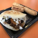 Arepa y tequeños servidos en un plato.