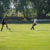 Two men playing a soccer match on a sunny outdoor field.