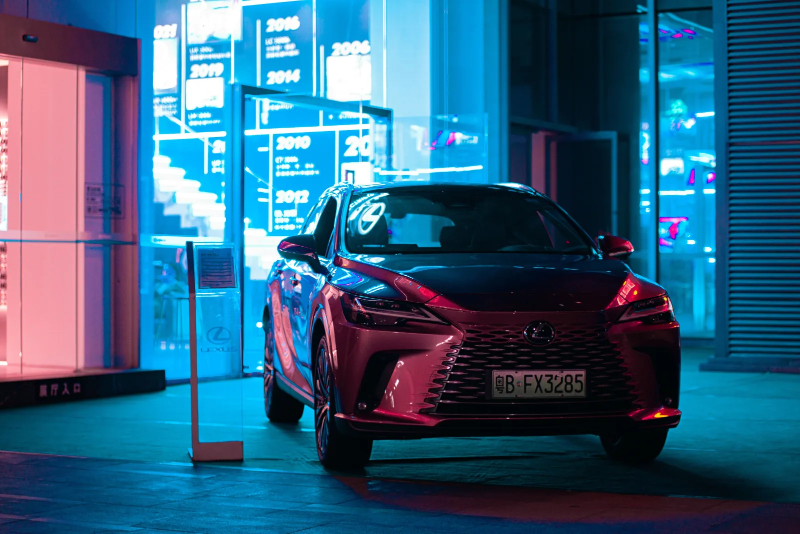 Elegante SUV Lexus estacionado de noche, que destaca el lujo en un paisaje urbano con vibrantes luces de neón.