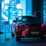 Elegante SUV Lexus estacionado de noche, que destaca el lujo en un paisaje urbano con vibrantes luces de neón.