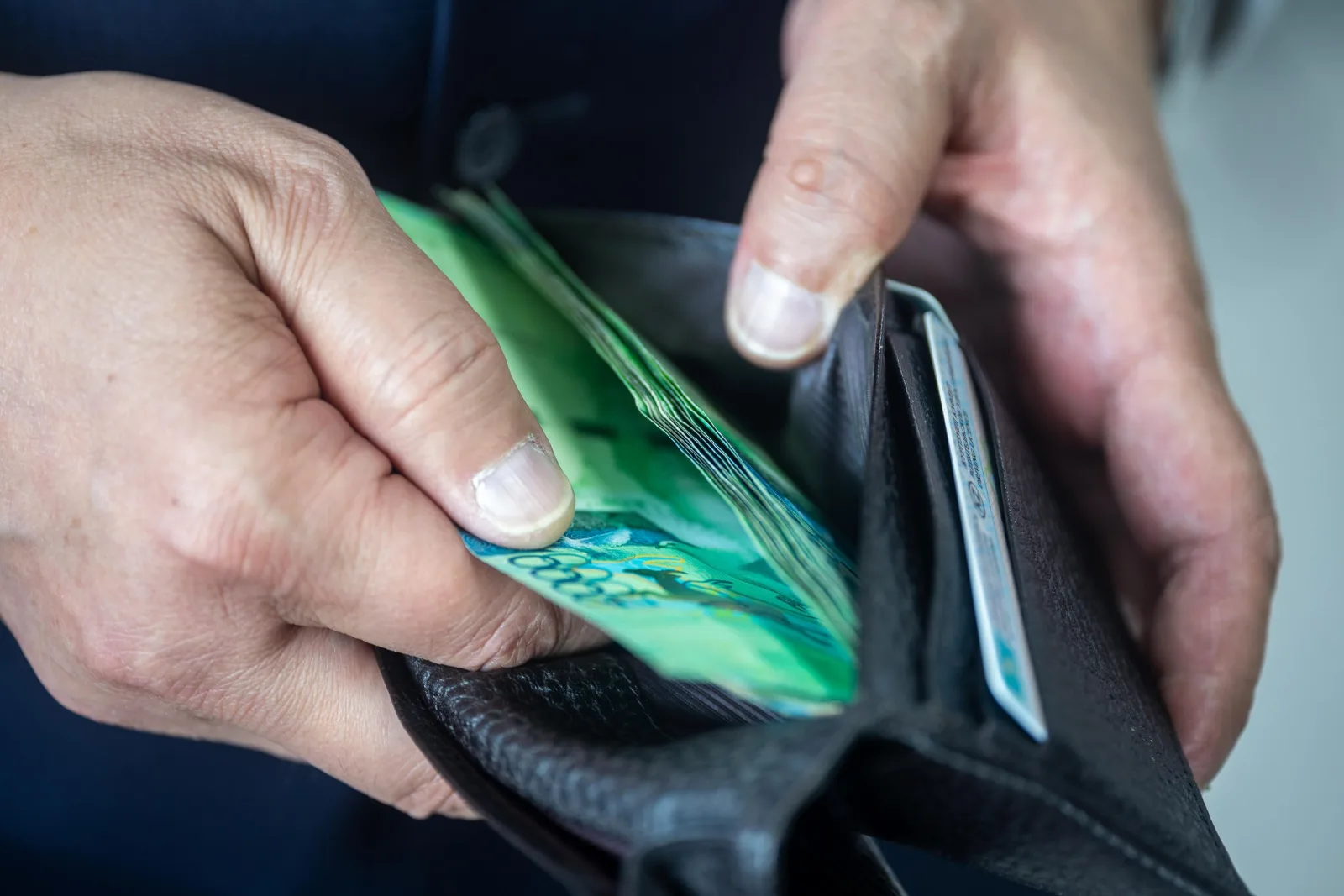 Vista en primer plano de una persona sosteniendo una cartera con moneda. Ideal para temas financieros o económicos.