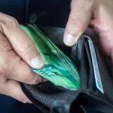 Vista en primer plano de una persona sosteniendo una cartera con moneda. Ideal para temas financieros o económicos.