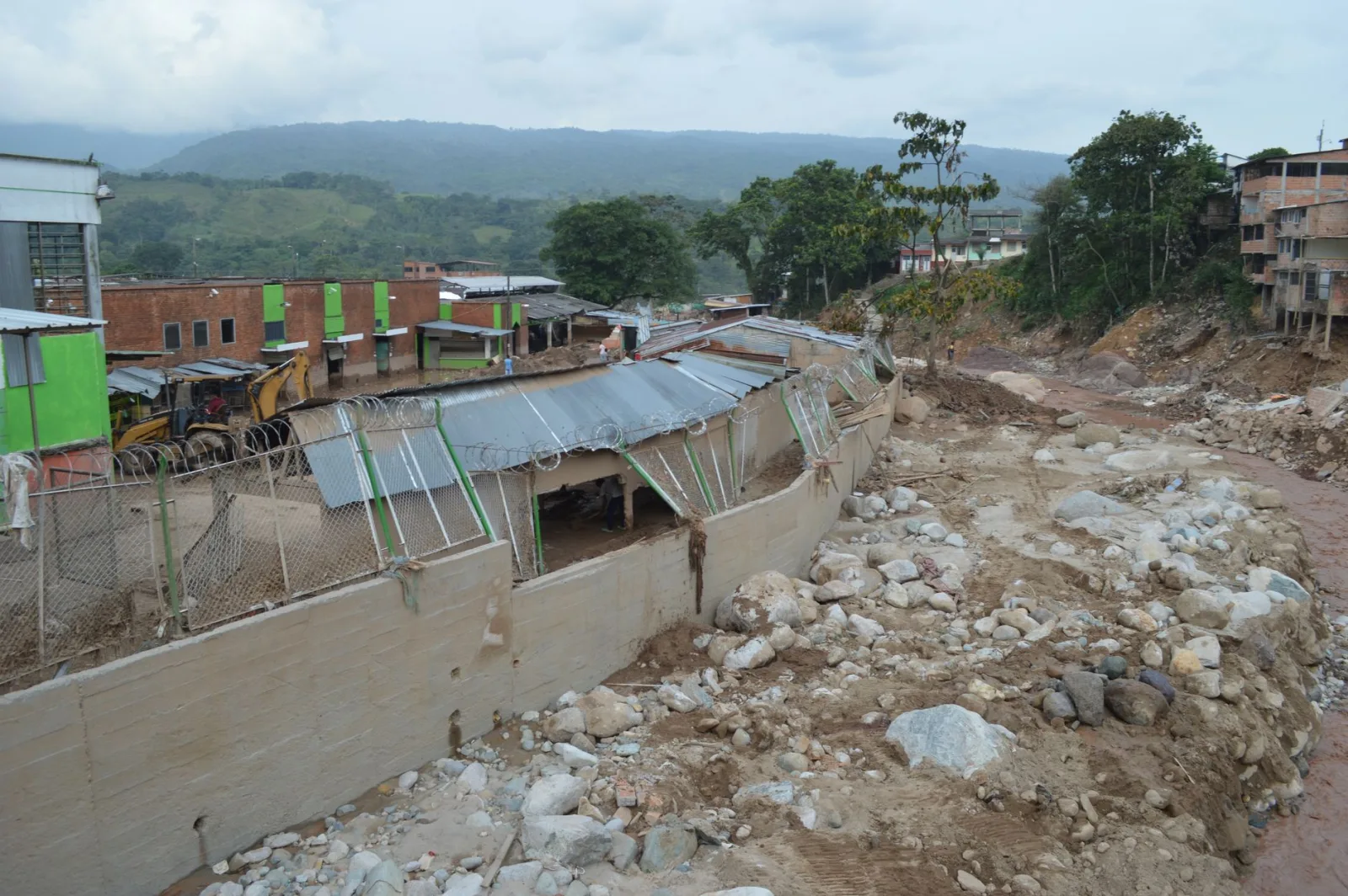 Paisaje erosionado en Mocoa, Colombia, que muestra la devastación rural y los edificios afectados por el desastre natural.