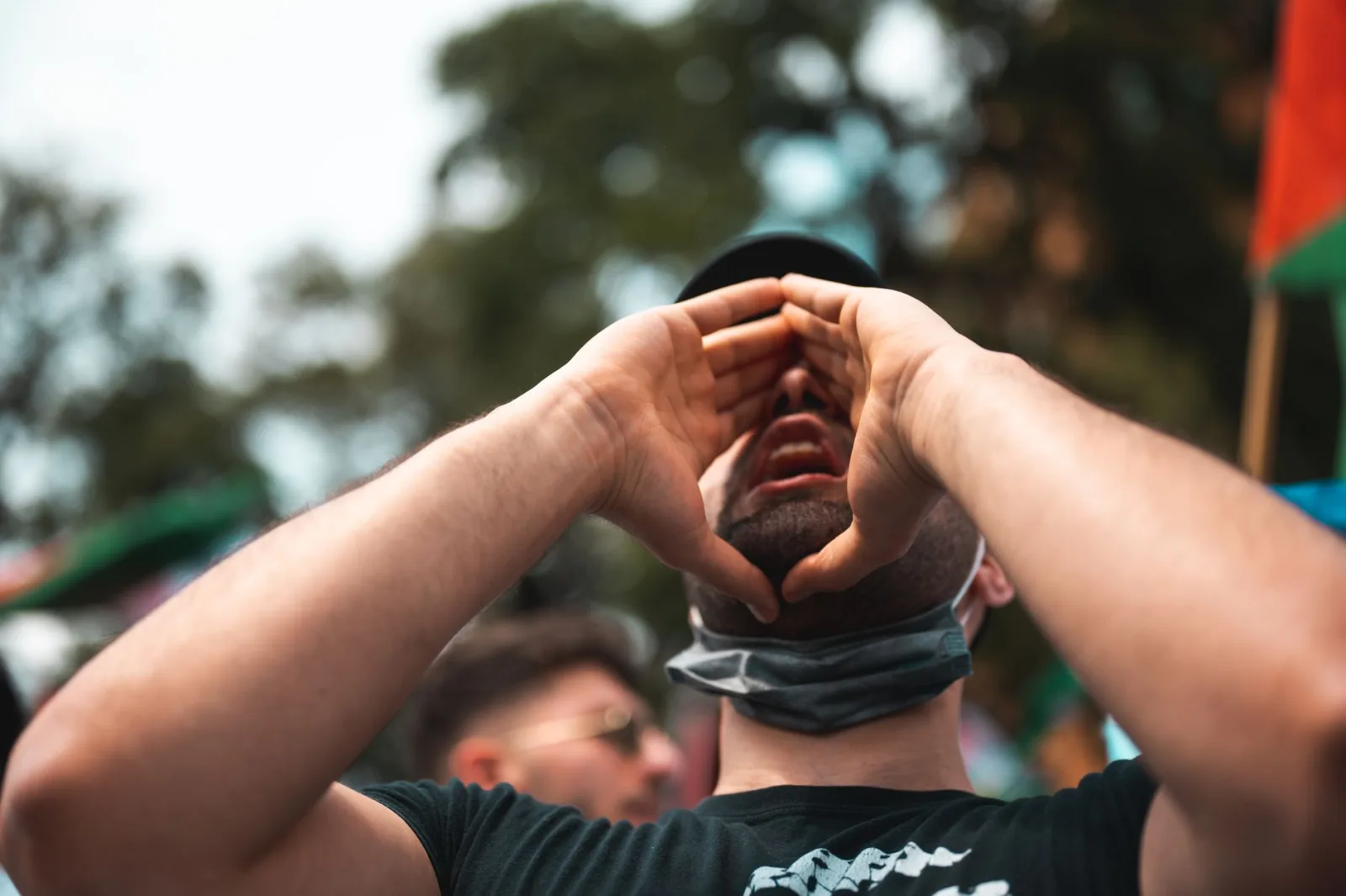 Un hombre grita apasionadamente durante una protesta al aire libre, mostrando activismo y compromiso.
