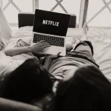 Una pareja relajándose juntos, viendo Netflix en una laptop en una habitación acogedora.