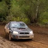 Un coche de rally todoterreno a toda velocidad por una pista embarrada en una zona boscosa de Polonia.