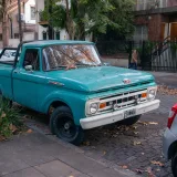 Antigua camioneta Ford azul estacionada en una calle arbolada de Buenos Aires, que muestra la cultura del automóvil clásico.