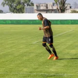 Un futbolista adulto trotando en un campo de césped durante un entrenamiento diurno.