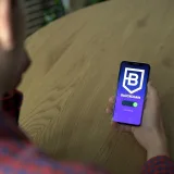 Person using a blockchain application on a smartphone indoors, showcasing technology.