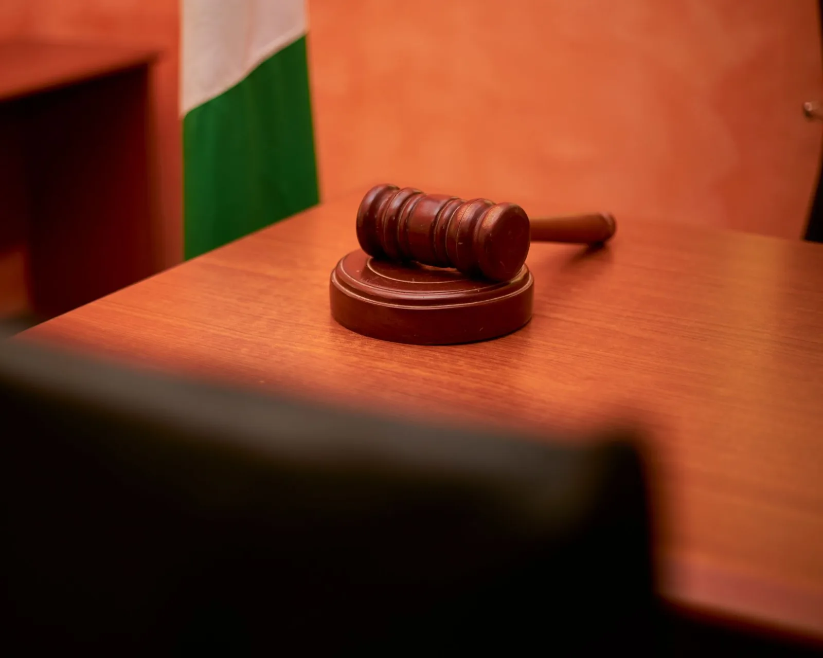 Un primer plano de un mazo judicial sobre el escritorio de una sala de audiencias, que representa la ley y la justicia.