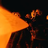 Un grupo de bomberos con equipo de protección combate las llamas durante una operación nocturna.
