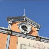 Detailed view of the clock tower at Nuevo Mercado, showcasing classic Spanish architecture under a clear blue sky.