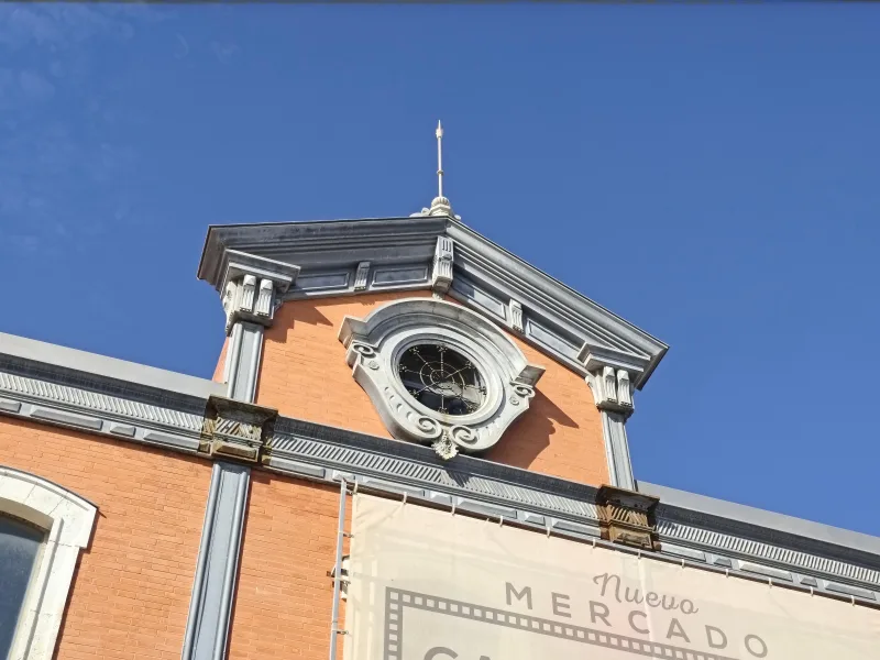 Detailed view of the clock tower at Nuevo Mercado, showcasing classic Spanish architecture under a clear blue sky.