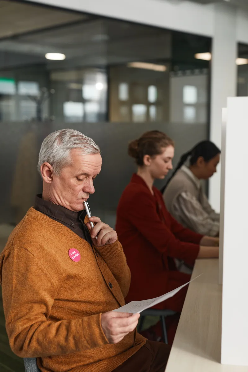 Hombre mayor revisando una papeleta en un colegio electoral cubierto el día de la votación.