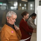 Senior man reviewing a ballot at an indoor polling station on voting day.