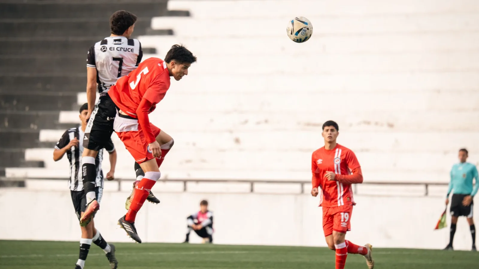 Jugadores de fútbol luchan por el balón en el aire durante un emocionante partido al aire libre.