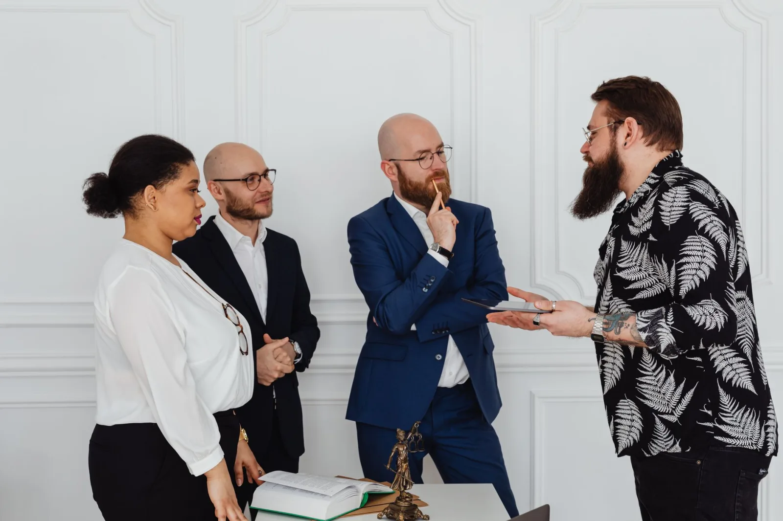 Grupo de profesionales en una oficina conversando sobre documentos e ideas durante una reunión.