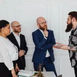 Grupo de profesionales en una oficina conversando sobre documentos e ideas durante una reunión.