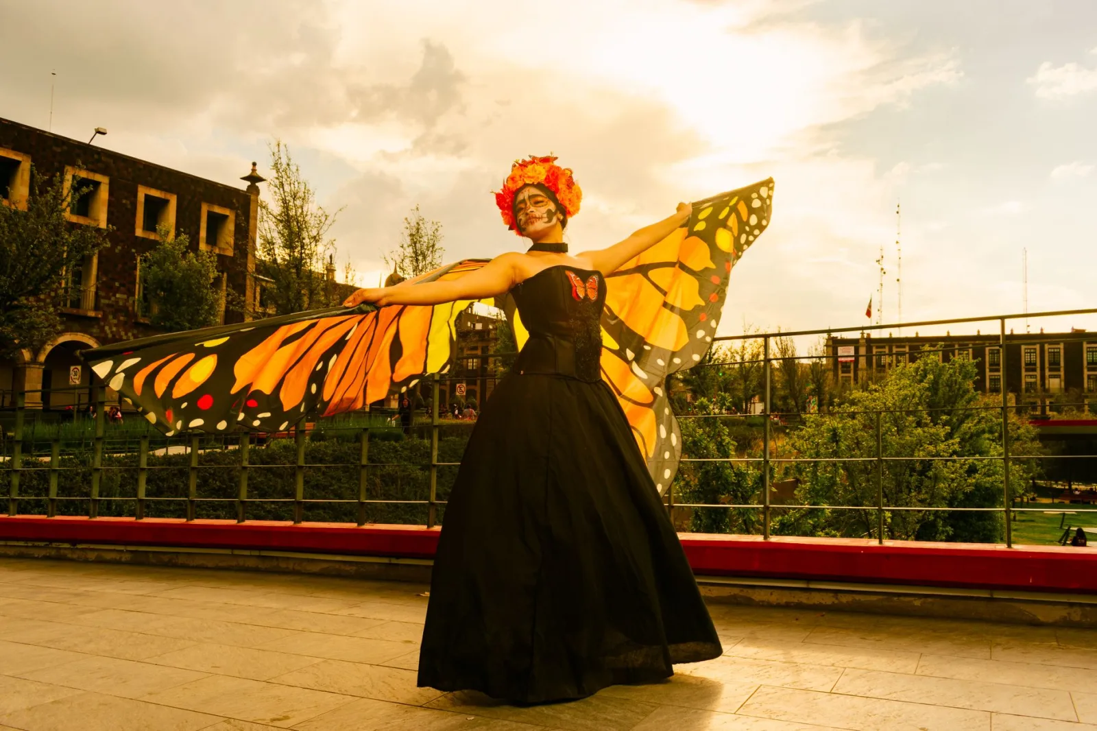Una mujer maquillada para el Día de Muertos y vestida de mariposa monarca posa al aire libre al atardecer en Toluca, México.