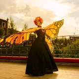 Una mujer maquillada para el Día de Muertos y vestida de mariposa monarca posa al aire libre al atardecer en Toluca, México.