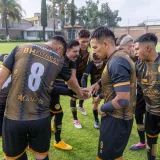 Soccer players in a team huddle on a sunny day at Texcoco, México, displaying unity and teamwork.