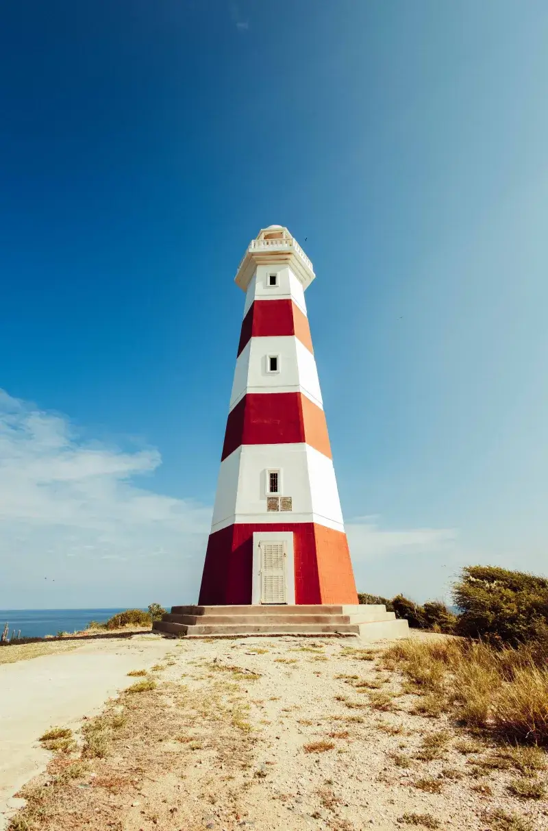 Striking red and white lighthouse on Margarita Island against a clear blue sky in Venezuela.