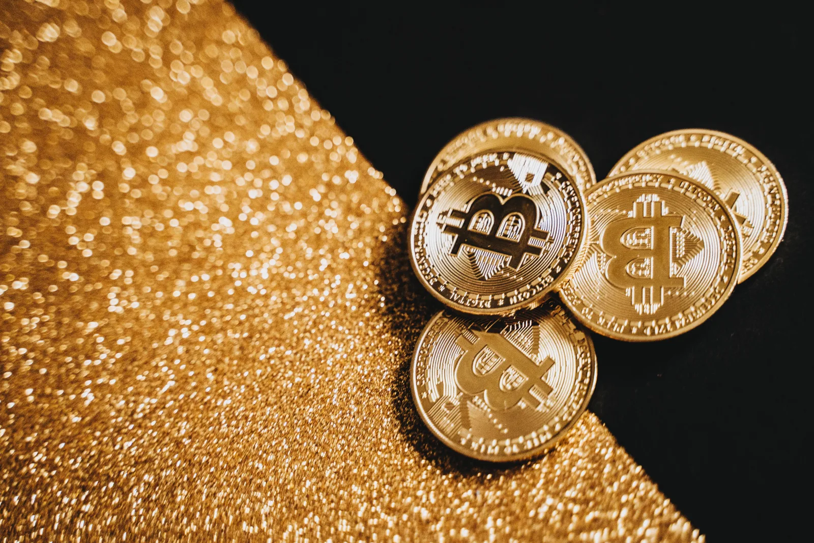 Monedas de Bitcoin de oro sobre una textura dorada brillante, representando la moneda digital y las finanzas.