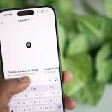 Mano sosteniendo un smartphone que muestra la interfaz de ChatGPT, rodeada de vegetación.