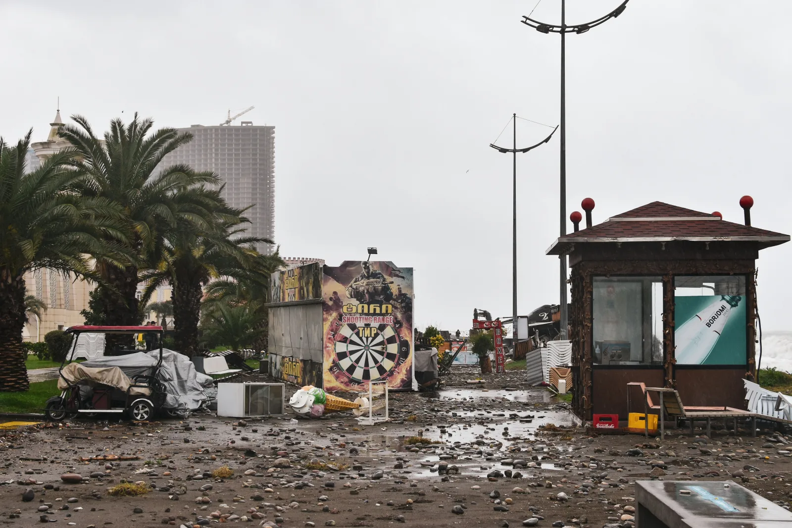 Calle de la ciudad llena de escombros de la tormenta y estructuras dañadas bajo un cielo nublado.