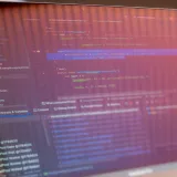 Vista enfocada de una pantalla de computadora que muestra código de programación con reflejos visibles.