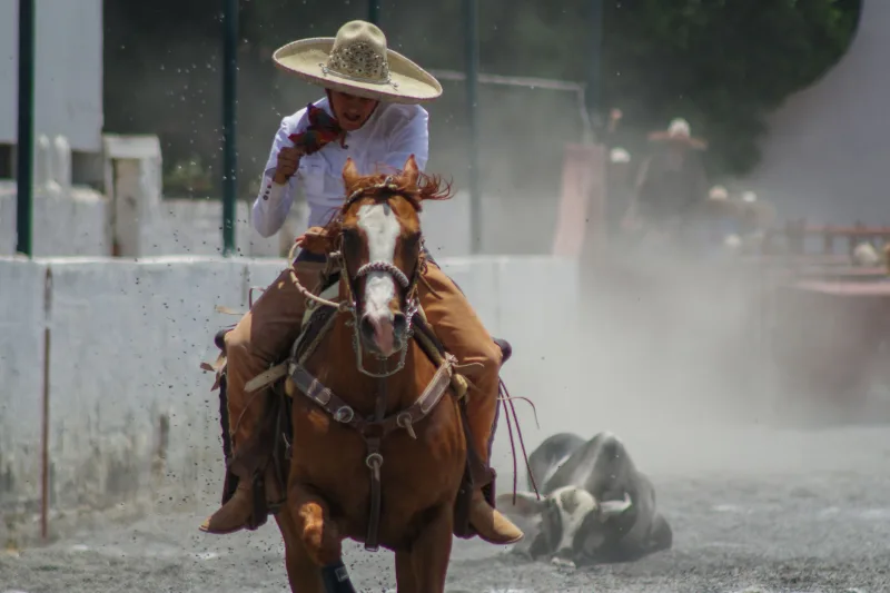 Dynamic action shot of a charro competing in a charreria event in Tlaxcala, Mexico.