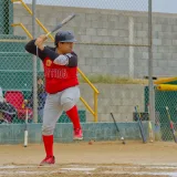 Jugador de béisbol aficionado bateando en un campo al aire libre, mostrando acción y concentración.