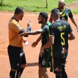 Un momento tenso en el campo mientras un árbitro le muestra una tarjeta a un jugador durante un partido de fútbol bajo el sol.