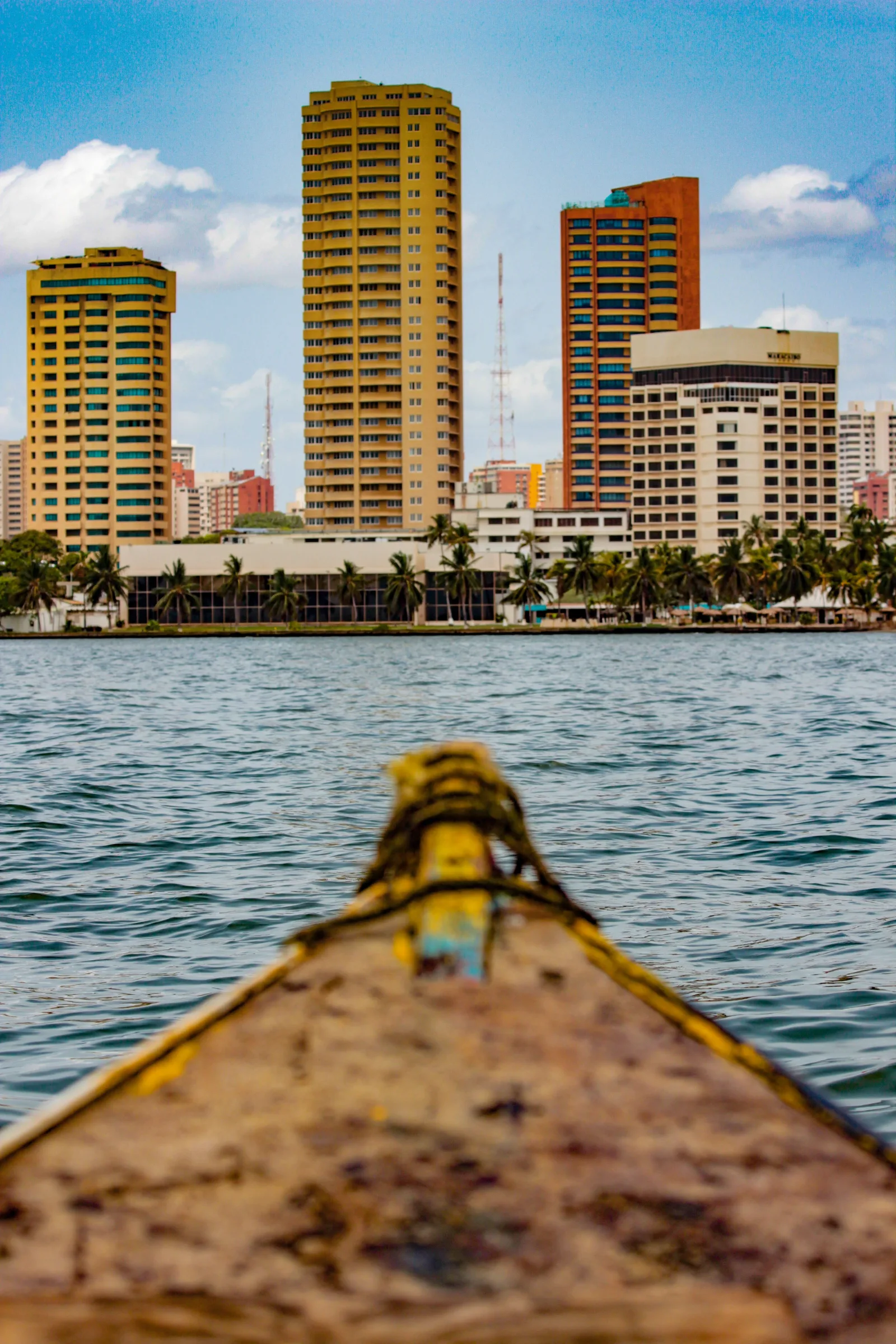 Vista panorámica del perfil urbano de Maracaibo desde una embarcación en el lago, con edificios altos y un día despejado.