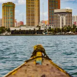 Vista panorámica del perfil urbano de Maracaibo desde una embarcación en el lago, con edificios altos y un día despejado.
