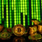 Stacks of golden bitcoins in front of a digital matrix, symbolizing cryptocurrency and blockchain technology.