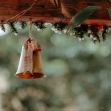 Una campana con un lazo de cuadros cuelga de una viga de madera, evocando un ambiente rústico y festivo.