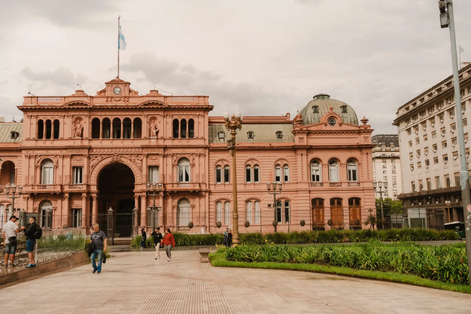 Vista frontal de la histórica Casa Rosada en Buenos Aires, Argentina, con personas en primer plano.