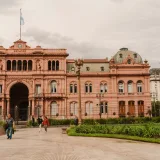 Vista frontal de la histórica Casa Rosada en Buenos Aires, Argentina, con personas en primer plano.
