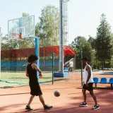 Dos hombres jugando al baloncesto en una cancha al aire libre durante el día.