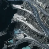 Aerial shot of an expansive open-pit mining operation with industrial machinery and mining layers visible.