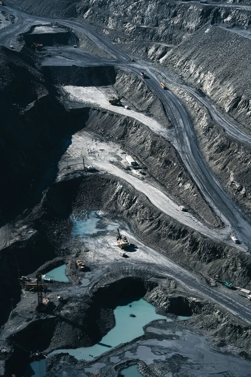 Aerial shot of an expansive open-pit mining operation with industrial machinery and mining layers visible.